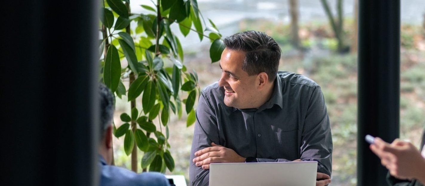 Synergy-trainer kijkt tevreden naar collega's na een succesvol webinar.