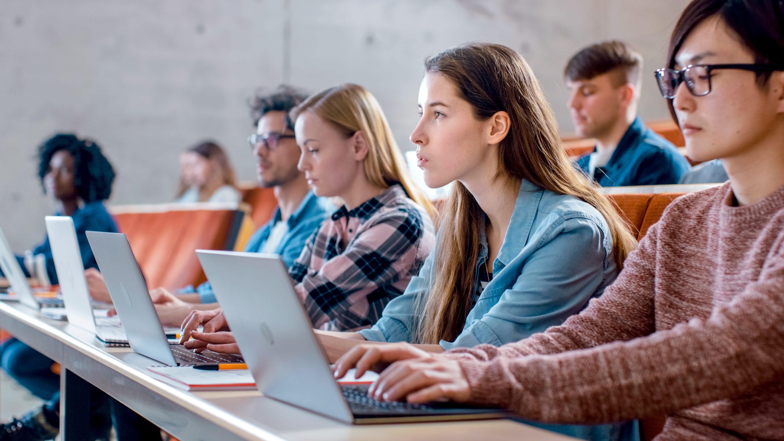 Studenten zitten in een collegebank met laptops
