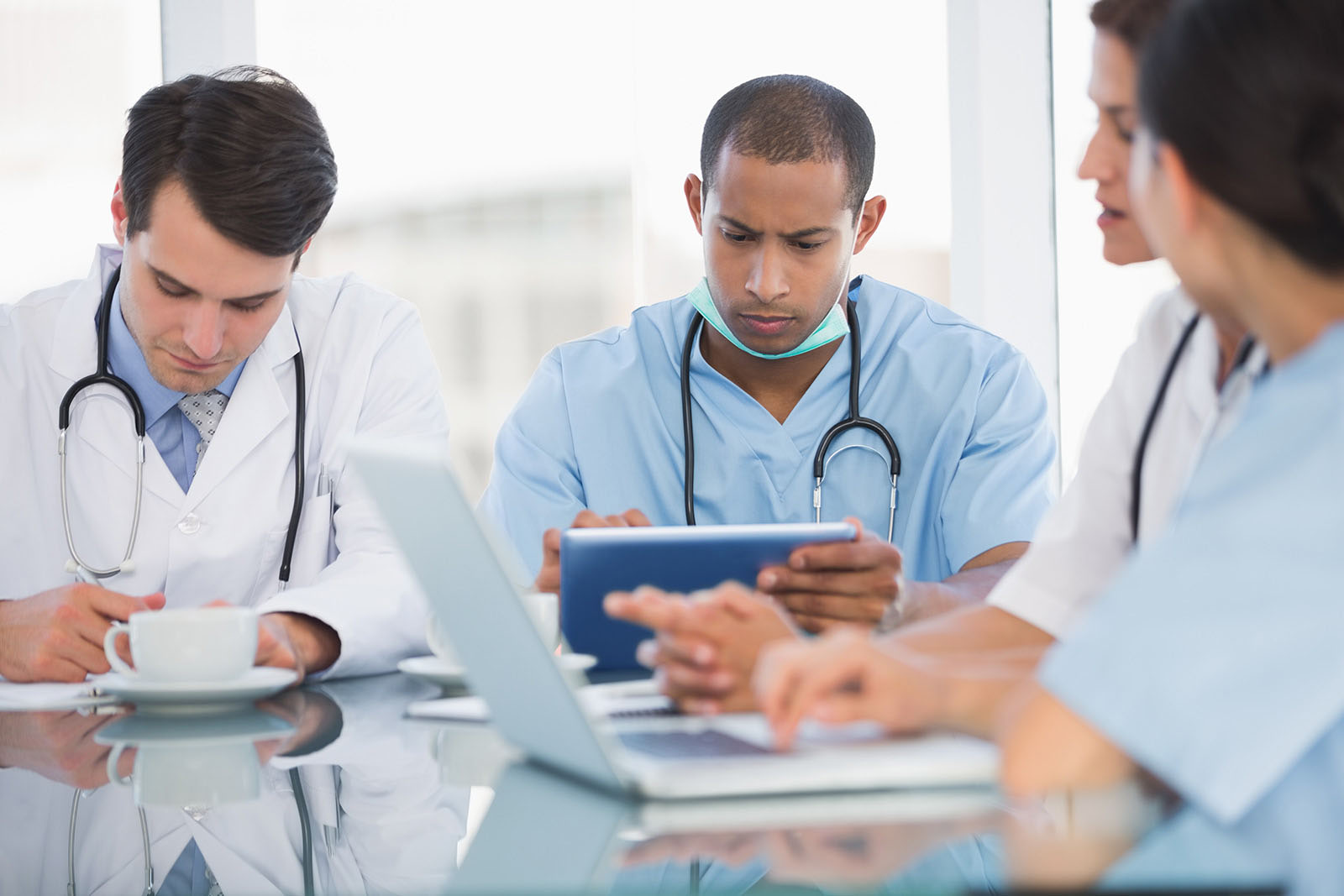 Artsen zitten aan een tafel te werken op een tablet