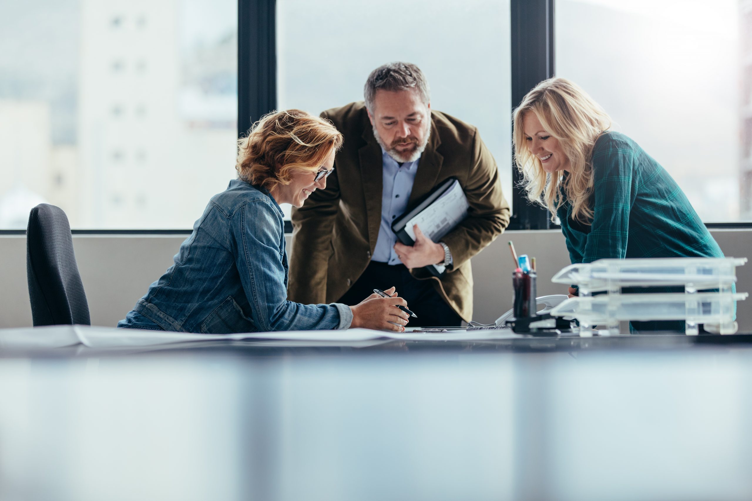 Drie collega&#039;s aan een bureau verbeelden de samenwerking tussen Axians, TransitieProfs en Hewlett Packard Enterprise