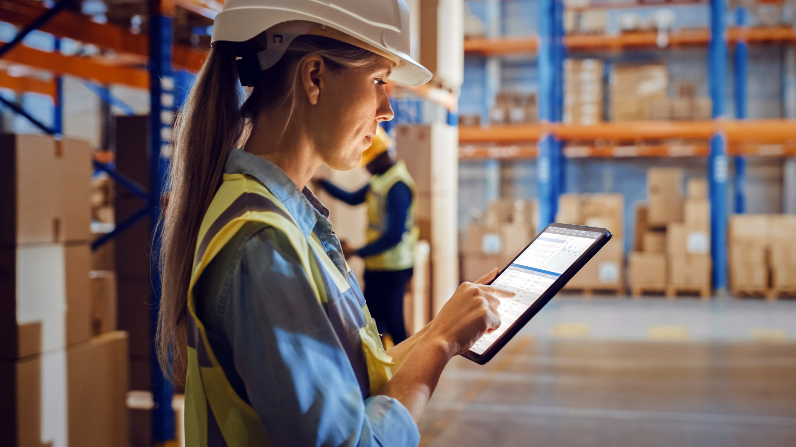 Vrouwelijke werknemer controleert voorraadbeheer bij op tablet, maakt gebruik van ict en netwerbeheer in logistiek