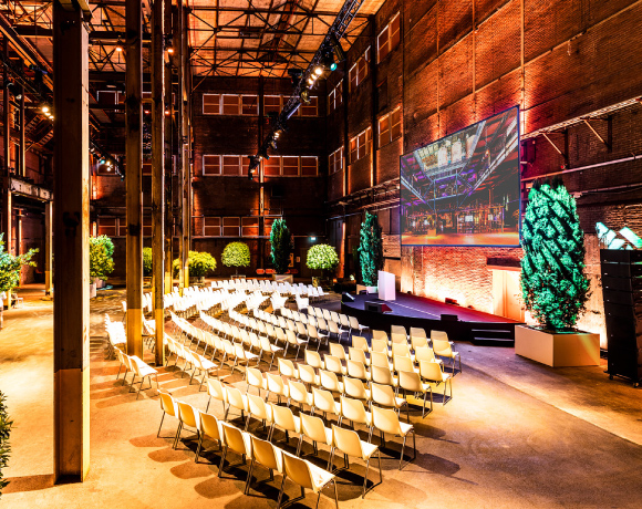 Foto van een van de zalen van de Sugar Factory, lege stoelen voor een podium