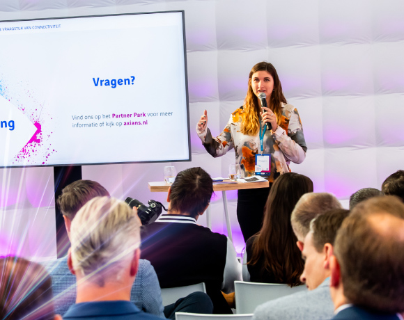 Foto presentatie vrouw naast een TV scherm en voor publiek