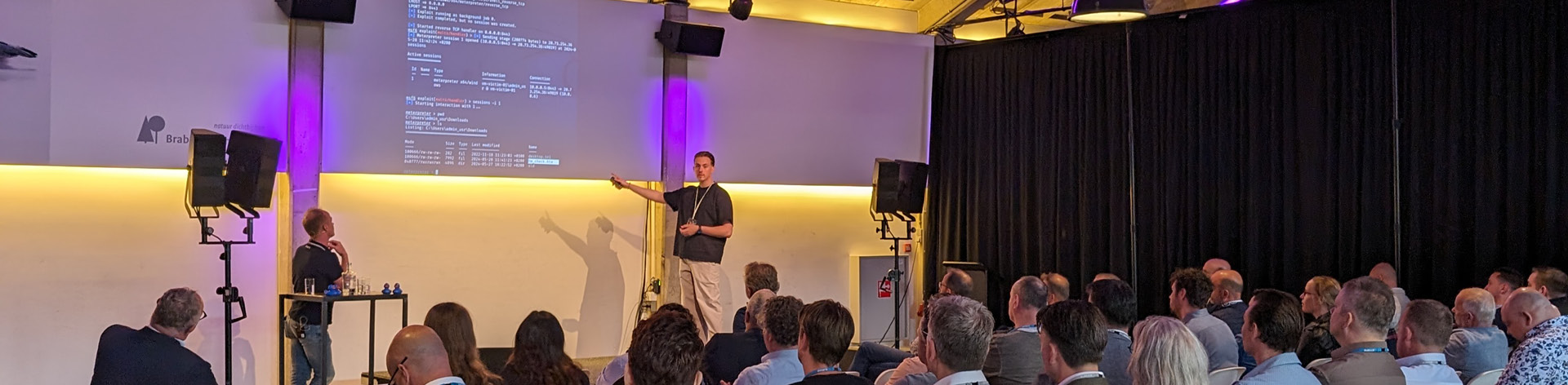 Twee collega&#039;s staan op het podium om te presenteren over het SOC tijdens het Cyber Security Event