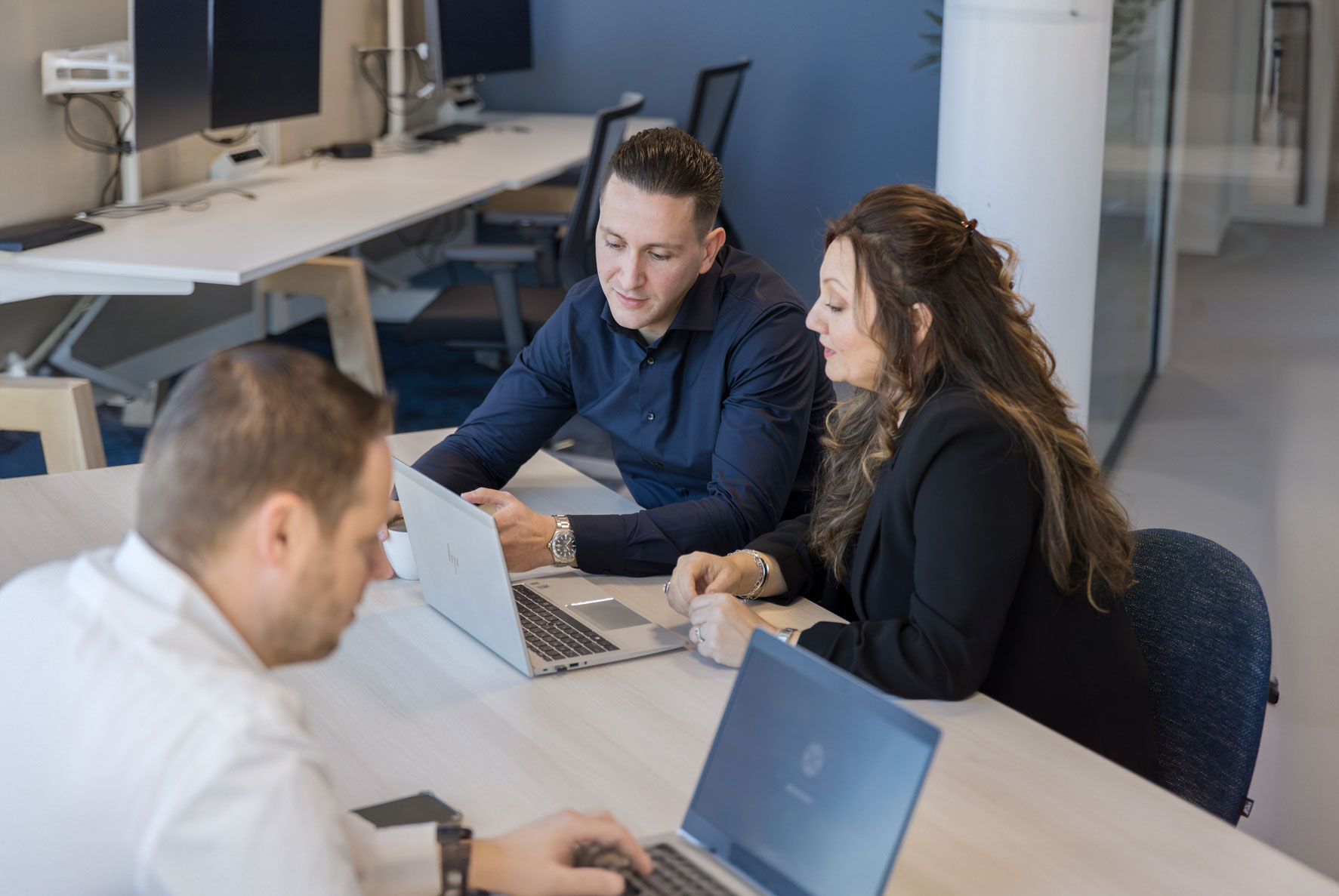 Cyber Squad collega&#039;s in overleg terwijl andere collega iets opzoekt op zijn laptop