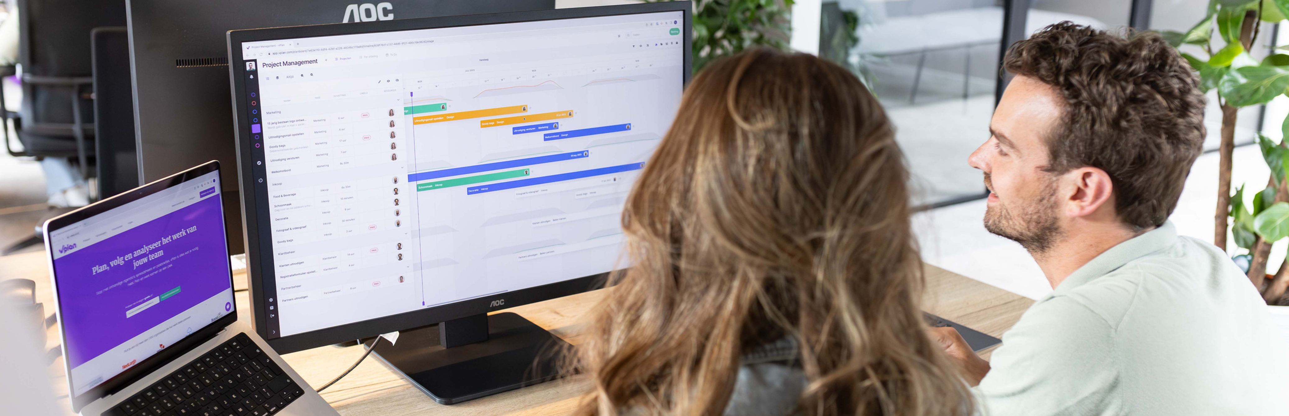 Twee mensen kijken tevreden naar hun planning via vPlan-software
