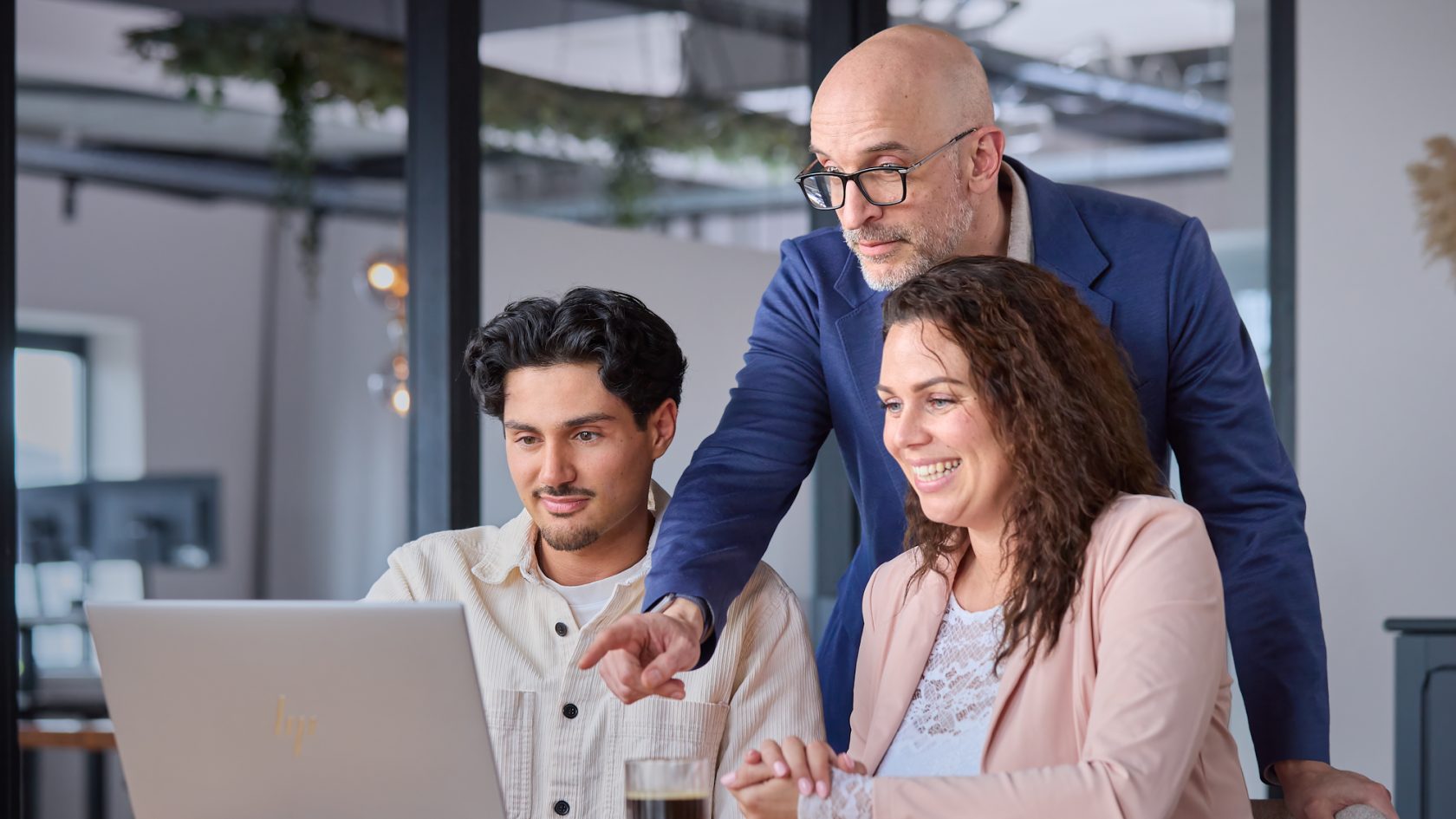 Synergy-expert spreekt achter laptop met 2 collega's over handige functionaliteiten in Exact Synergy