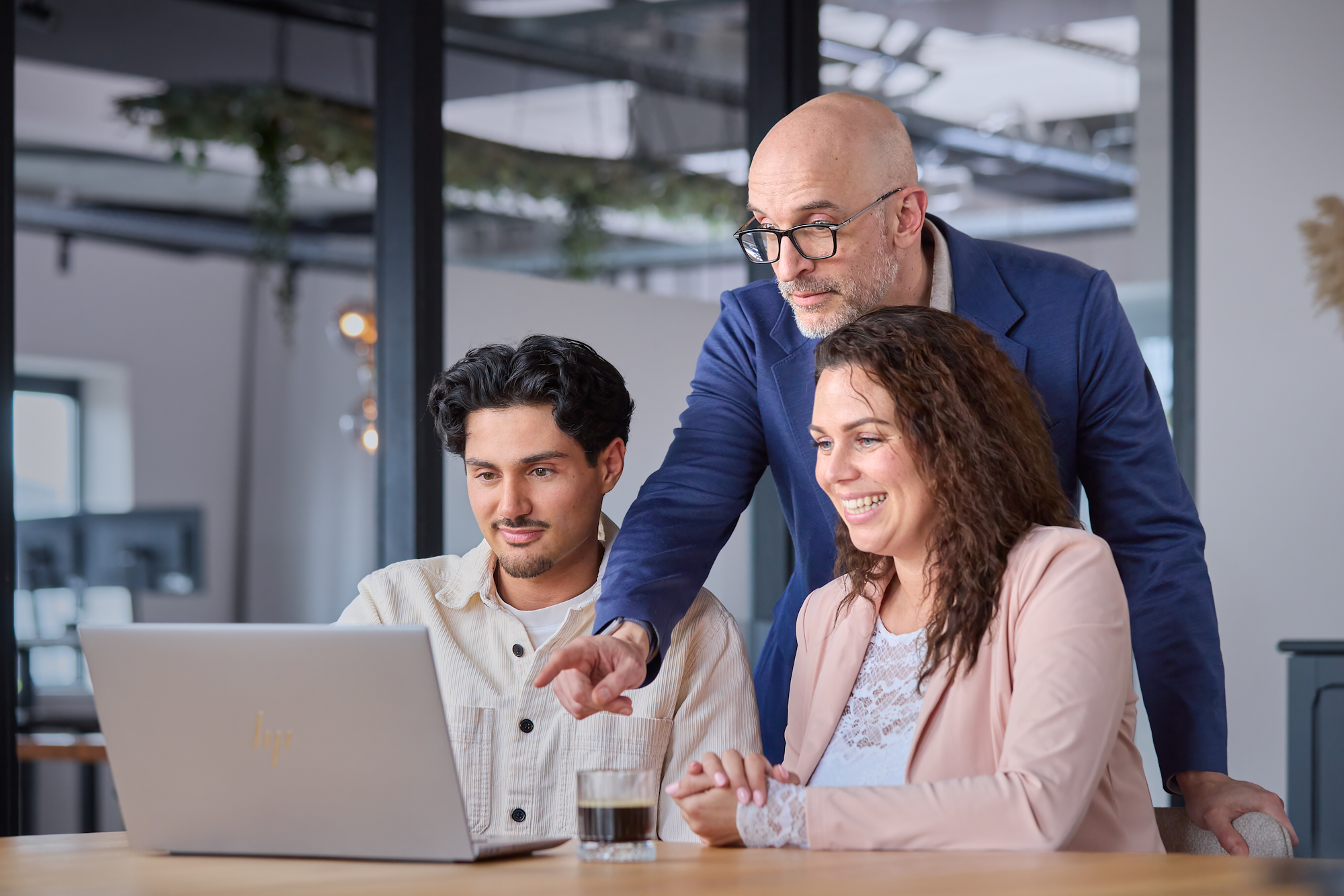 Synergy-expert spreekt achter laptop met 2 collega's over handige functionaliteiten in Exact Synergy